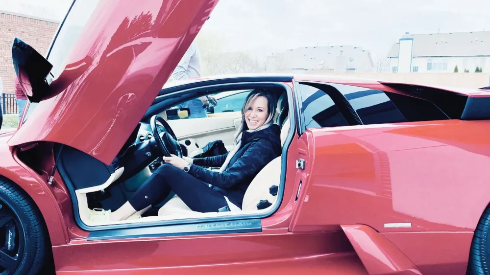 Jill Salajka behind the wheel of a Lamborghini with scissor doors raised
